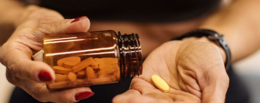 Woman in menopause pouring a vitamin supplement from a bottle into her hand